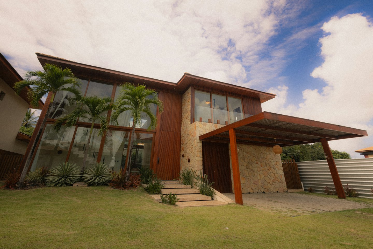 Rumah modern dengan detail kaca, kayu, dan batu.